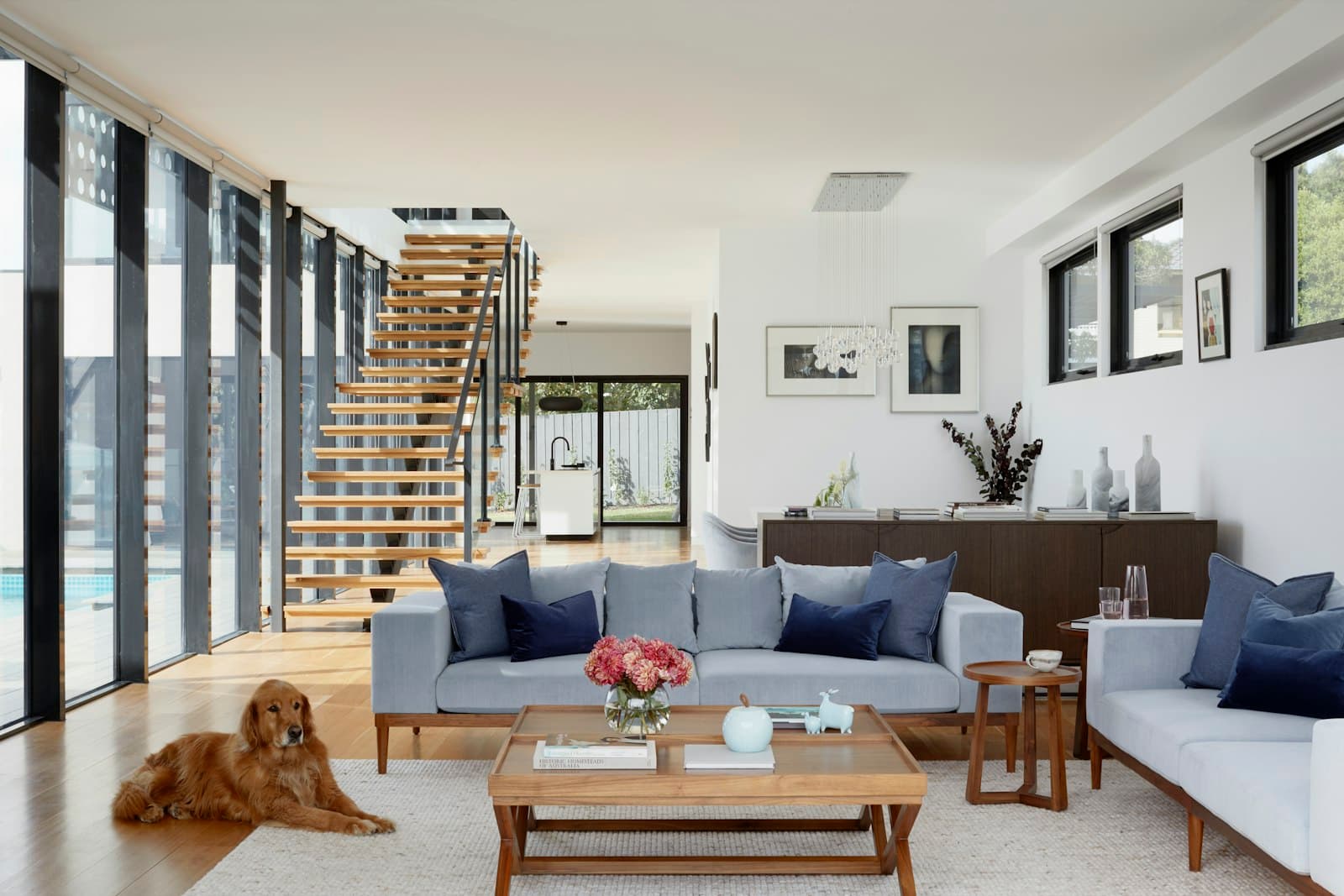 Open plan Australian living space opening to a pool through black framed doors